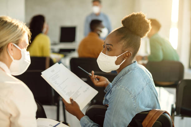 I thought I would get a better grade on a test! African American college student with a face mask talking to her friend about exam results in lecture hall. kn95 face mask photos stock pictures, royalty-free photos & images