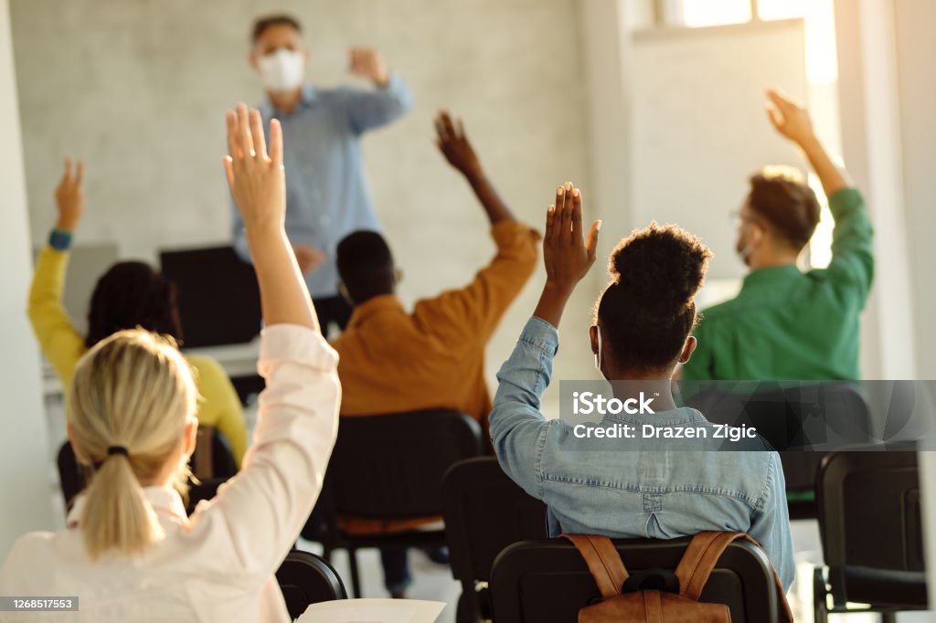 在演講廳上課時, 一群學生舉起雙臂的背視圖。 - 免版稅課室圖庫照片