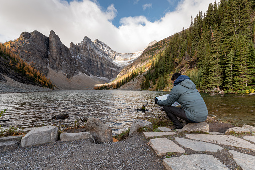 Man traveler sitting and looking map on Lake Agnes at Banff national park, Canada