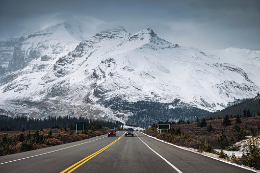 Car on highway and snowy mountain range in gloomy at Icefields Parkway, Canada