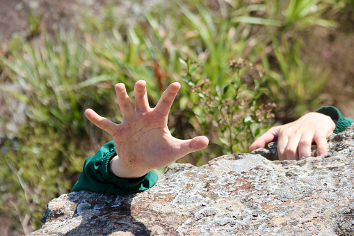 Staging of a person hanging by a hand over an abyss calling for help
