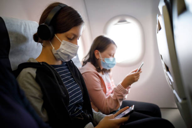 istock Kids with face protective mask using mobile phone in airplane 1268533738