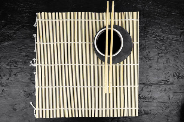 Japanese kitchen background with bamboo mat, chopsticks, soy sauce on black background