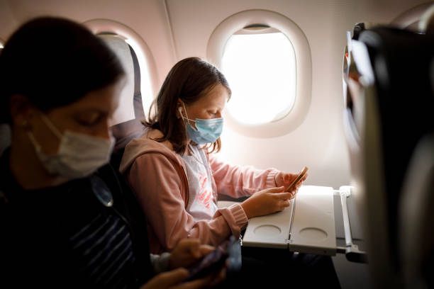 istock Kids with face protective mask using mobile phone in airplane 1268534893