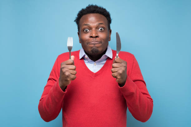 istock Hungry african man holding fork and knife raised waiting for dinner. 1268535169