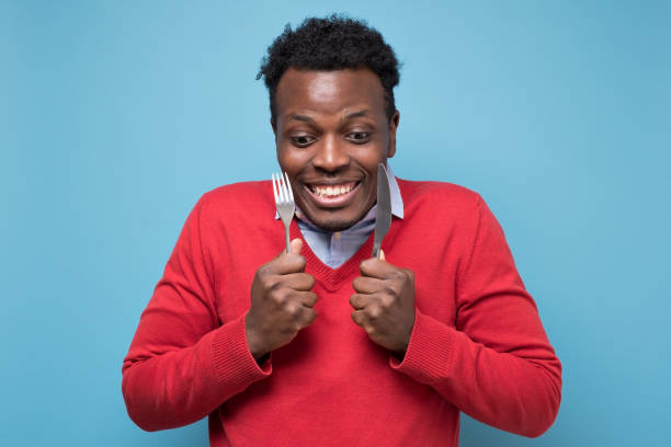 istock Hungry african man holding fork and knife raised waiting for dinner. 1268535209