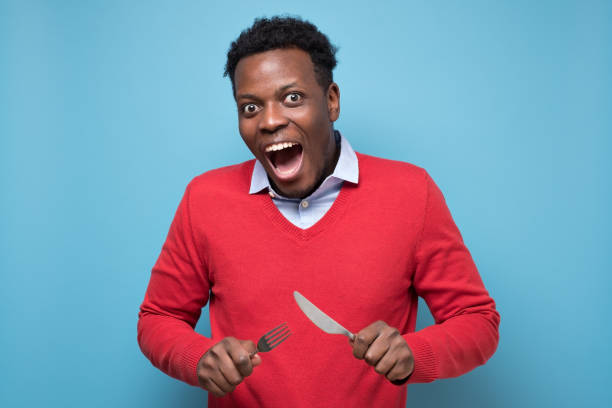 istock Hungry african man holding fork and knife raised waiting for dinner. 1268535281