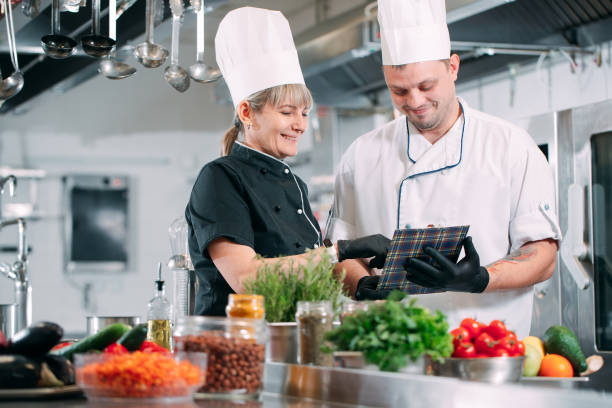Two chefs discuss the menu in the kitchen of a restaurant or hotel. stock photo