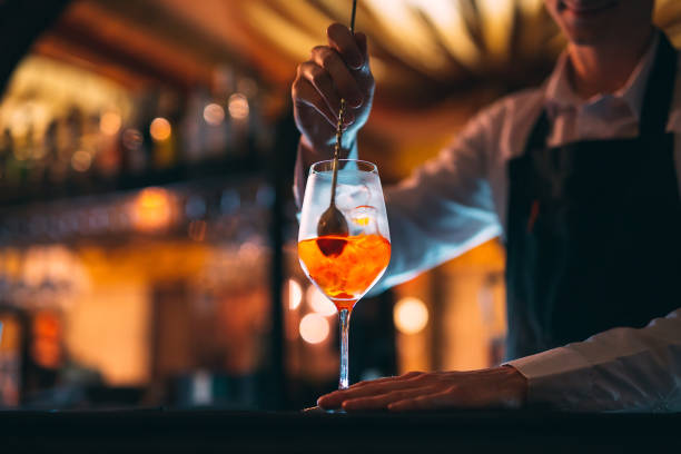 barman hand stirring a fresh and sweet orange summer cocktail with a spoon on the bar counter. - men elegance cocktail cool imagens e fotografias de stock