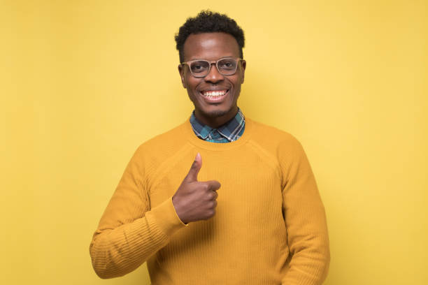 istock Handsome black man showing thumb up. Studio shot on yellow wall. 1268540330