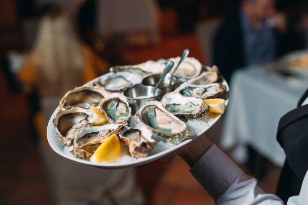 um garçom segura uma porção de ostras em um restaurante. - prepared oysters prepared shellfish shucked seafood - fotografias e filmes do acervo