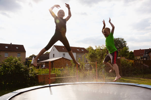 istock Girl and boy having water fun jumping on trampoline 1268540950