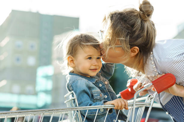 junge schöne mutter und ihr niedlicher kleiner sohn in einem einkaufswagen - baby beautiful little boys carrying stock-fotos und bilder