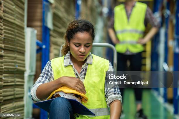 Young African Female Warehouse Worker Staff Feeling Sad And Upset While Sitting On The Floor Of The Storehouse Due To Been Fired From Job Cause By Company Bankruptcy From Coronavirus Pandemic Stock Photo - Download Image Now