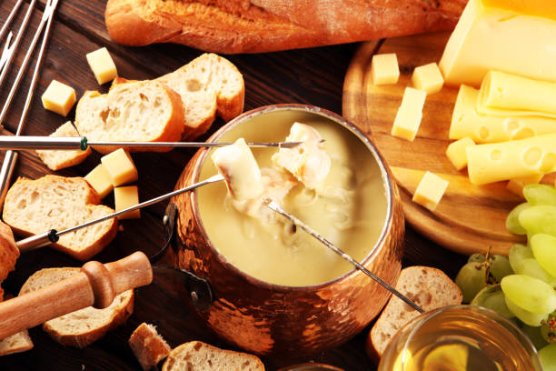 istock Gourmet Swiss fondue dinner on a winter evening with assorted cheeses on a board alongside a heated pot of cheese fondue with two forks dipping 1268544224