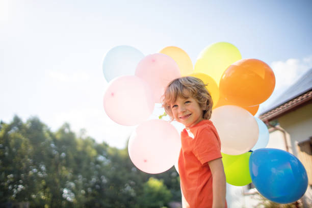 istock 4 years old boy with colorful balloons outside 1268546168