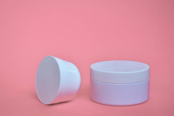 istock Round, white, plastic cosmetic jar, layout isolated on a pink background. 1268548325