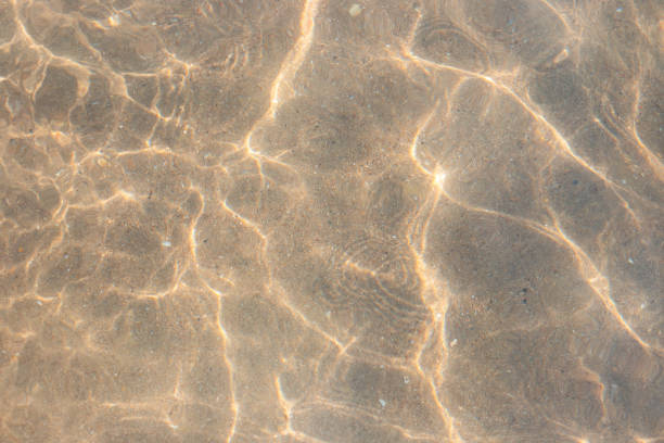 istock clear sea water with waves and sun reflection on the sandy bottom. Water texture 1268548618