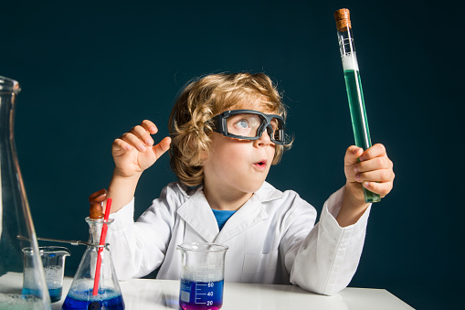 Portrait of a little boy in a lab coat doing a science experiment