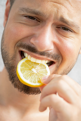 Young man eating a lemon