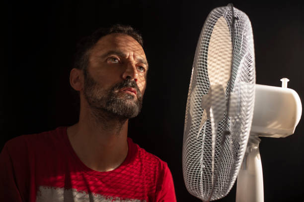 istock . middle-aged man fanning himself next to a fan 1268552217