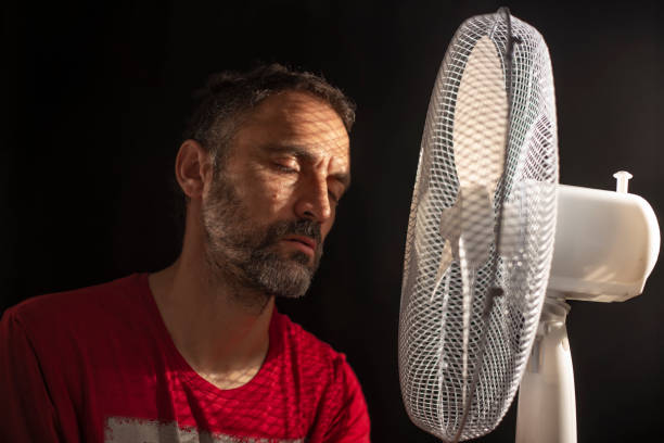 istock middle-aged man fanning himself next to a fan 1268552223