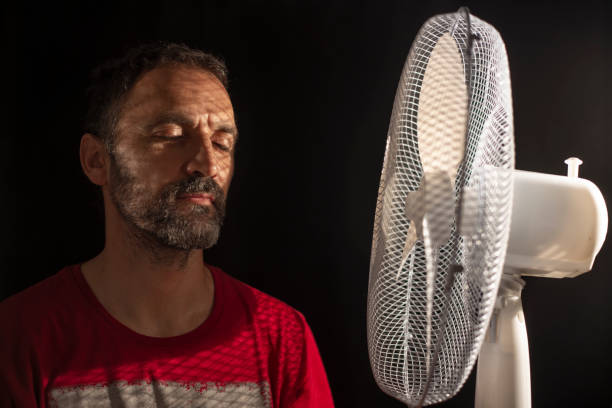 istock middle-aged man fanning himself next to a fan 1268552225