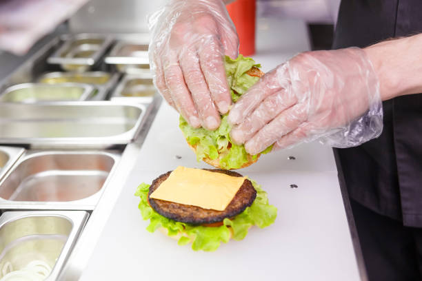 Cook adding a second half of the burger.