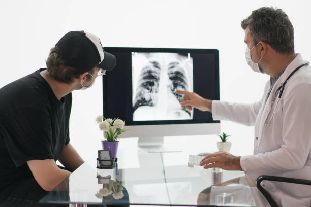 dojrzały mężczyzna lekarz patrzy na radiografii klatki piersiowej ze swoim pacjentem. - x ray x ray image chest human lung zdjęcia i obrazy z banku zdjęć