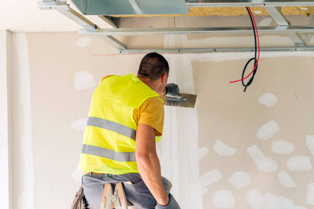 istock Thirty years old manual worker with wall plastering tools inside a house. Plasterer renovating indoor walls and ceilings with float and plaster. 1268559663