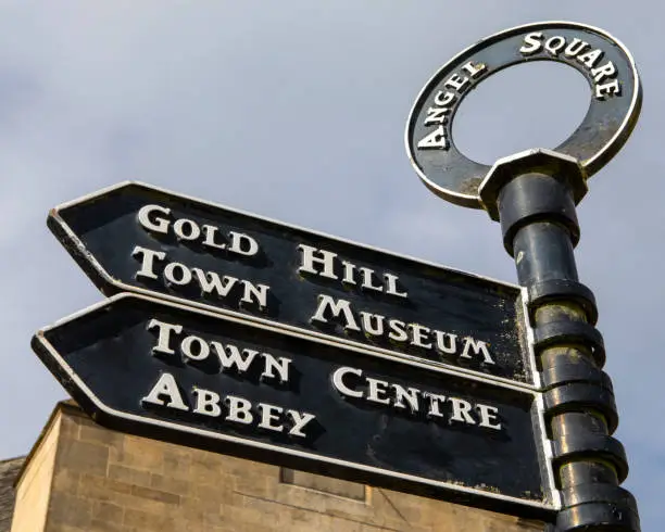 A signpost in Angel Square in the historic town of Shaftesbury in Dorset, UK. The sign points visitors into the direction of popular landmarks - Gold Hill, Museum and Abbey.