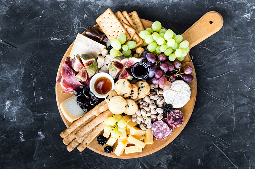 Charcuterie board. Cheese platter: Parmesan, maasdam, camembert, cheddar, gouda with prosciutto, salami, fruits and nuts. Assortment of tasty appetizers or antipasti. Top view. Copy space.