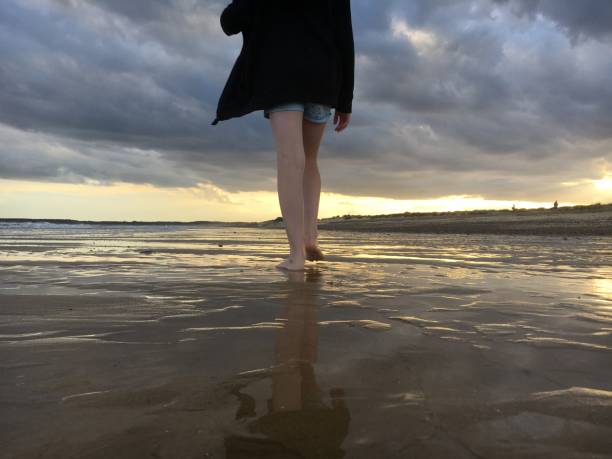sunset walberswick playa suffolk mar con reflejos de las nubes niña caminando en la playa - 7676 fotografías e imágenes de stock