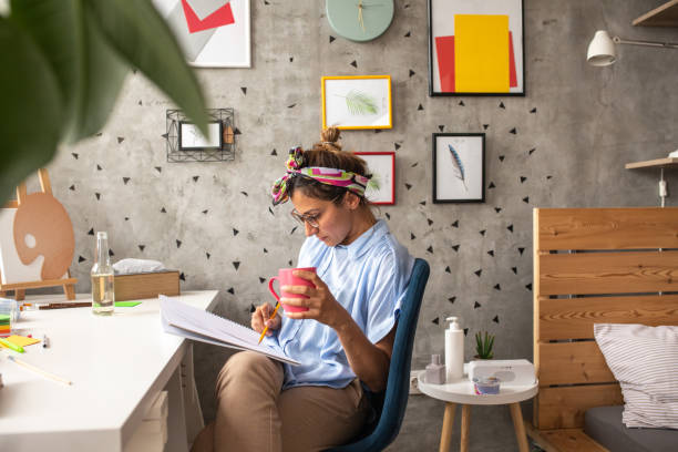 Female artist drawing at home Female artist sitting at desk in living room and drawing, at home illustrator stock pictures, royalty-free photos & images