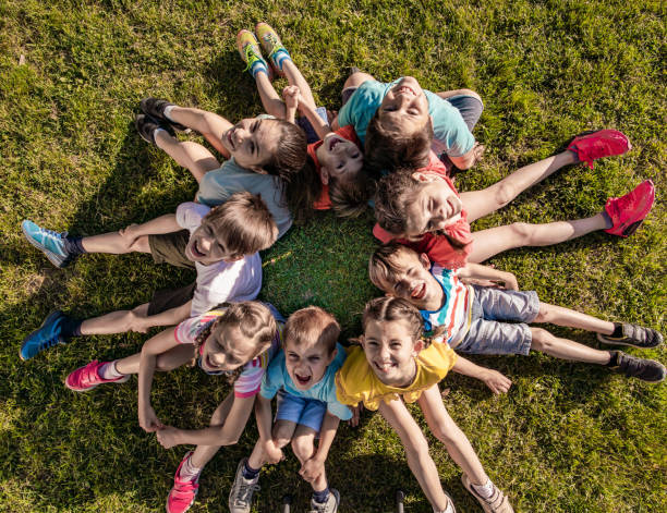istock Happy kids sitting in circle on the grass 1268566910