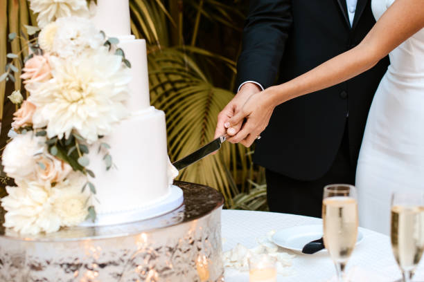 花の装飾と上に新郎新婦の置物と3つの階層化された白いウェディングケーキ。 - wedding reception ストックフォトと画像