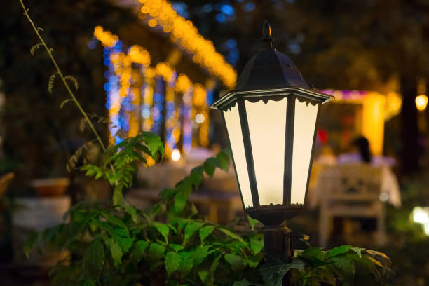 街路照明の鉄レトロなランタンは、花輪の誰も背景のボケボールで、裏庭のクローズアップの夜の庭で暖かい光で輝きます。 - lighting equipment defocused street light city ストックフォトと画像