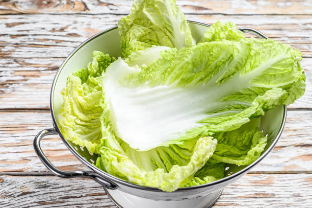 istock Fresh Chinese cabbage leaves in a colander. White wooden background. Top view 1268576711
