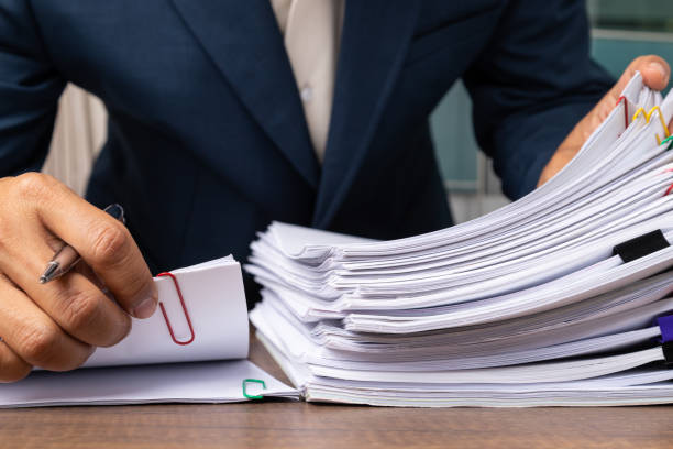 istock Man hand pick up Stack overload document report paper with colorful paperclip, business and paperless concept. 1268576820