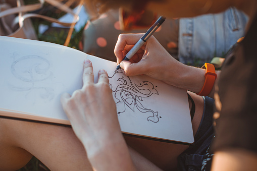 La mujer dibuja cartas en el parque. Esbozar letras a mano en un cuaderno de bocetos photo