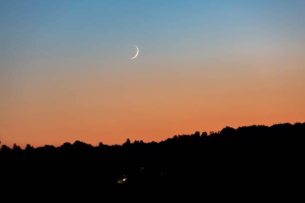 istock A young moon on an orange-blue sunset sky over a dark forest. Horizontal orientation. High quality photo 1268577962