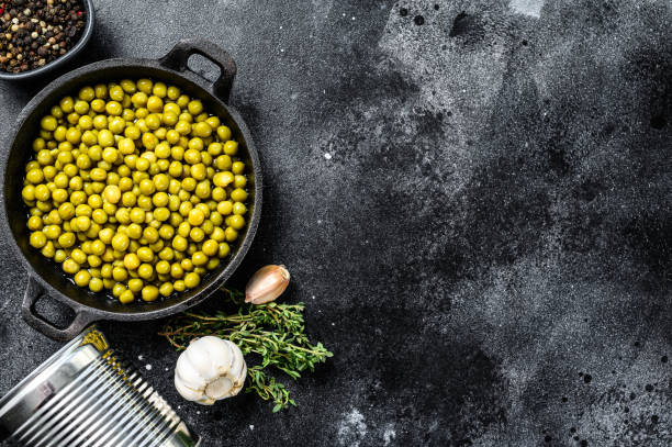 istock Green peas in a cast-iron bowl. Canned food. Black background. Top view. Copy space 1268582000