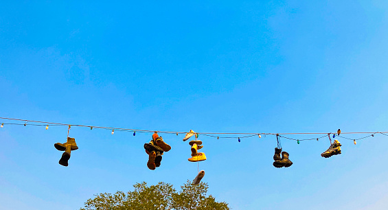 Sport Shoes Hanging on Overhead Wire, Blue Sky Background