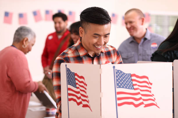 istock Mid-adult, Asian descent man votes in USA election. 1268583602