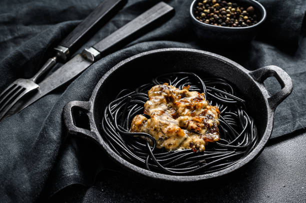 istock Black spaghetti pasta with squid ink in a pan. Beef in pepper sauce. Black background. Top view 1268583791