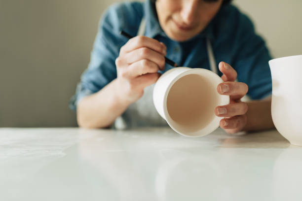 istock Woman Artisan Drawing on Ceramic Cup 1268585352