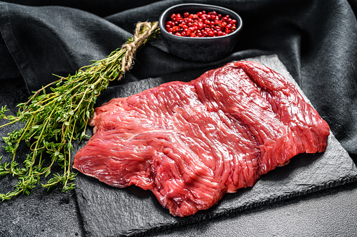 Raw outside skirt steak, marbled meat. Black background. Top view.