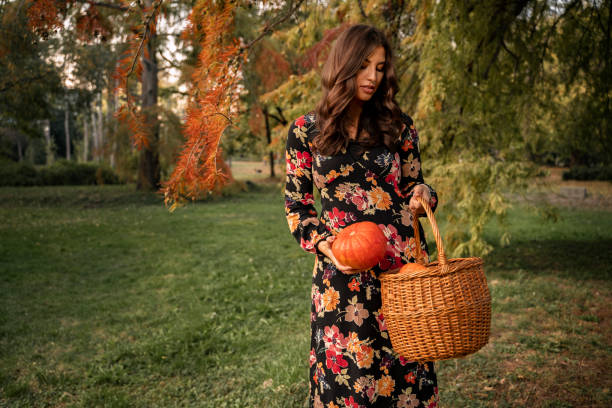 istock Attractive, stylish young brunette putting pumpkin in basket 1268587108