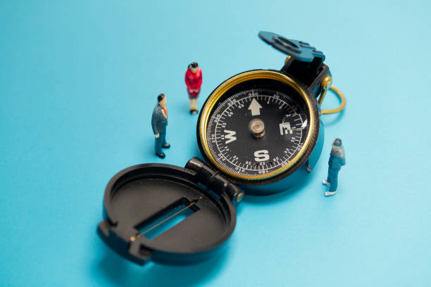 istock Miniature businessman and compass on blue background 1268595701