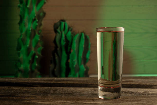 detail of tequila shot on a wood table with a cactus in background detail of tequila shot on a wood table with a cactus in background peyote cactus stock pictures, royalty-free photos & images